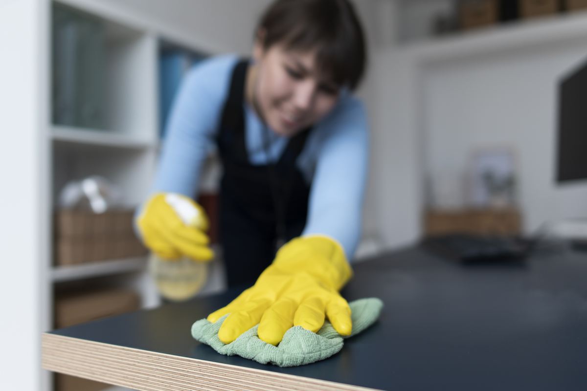 Cleaning professional in gloves wiping a desk in a business space