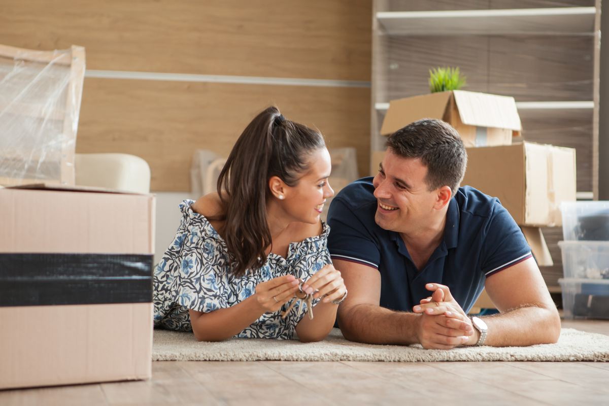 Happy couple relaxing on the floor of their new home on moving day
