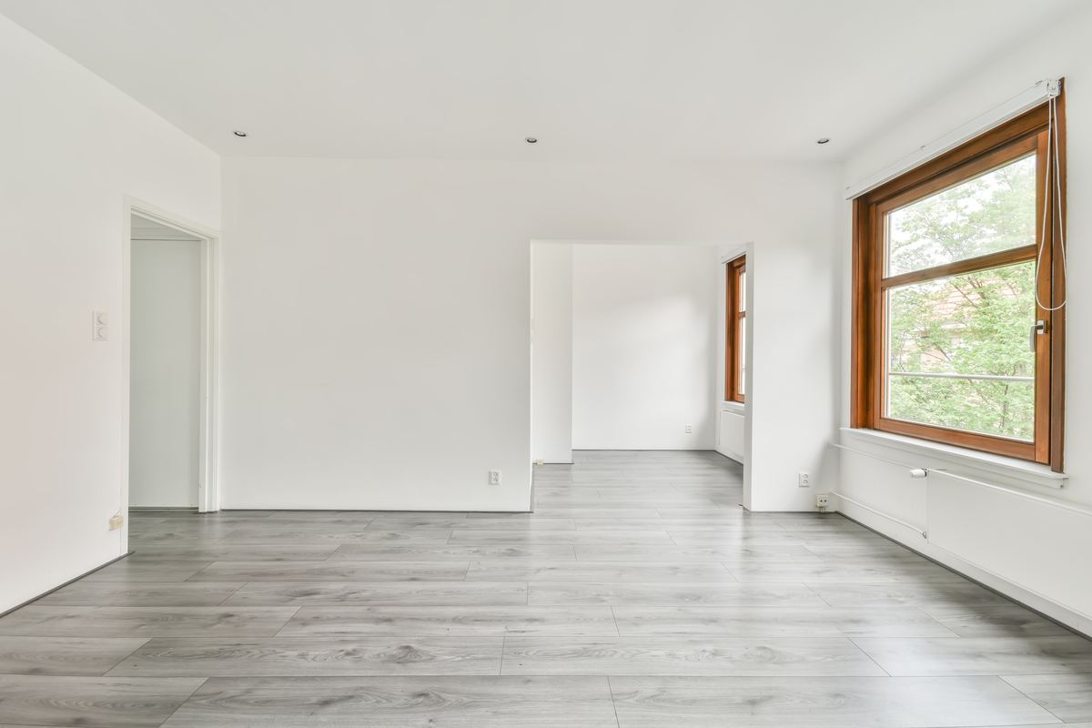 Bright, empty renovated room with new floors and large windows