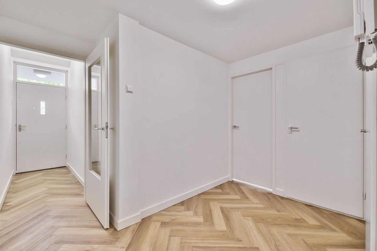 Freshly renovated hallway with white walls and new wood flooring after construction