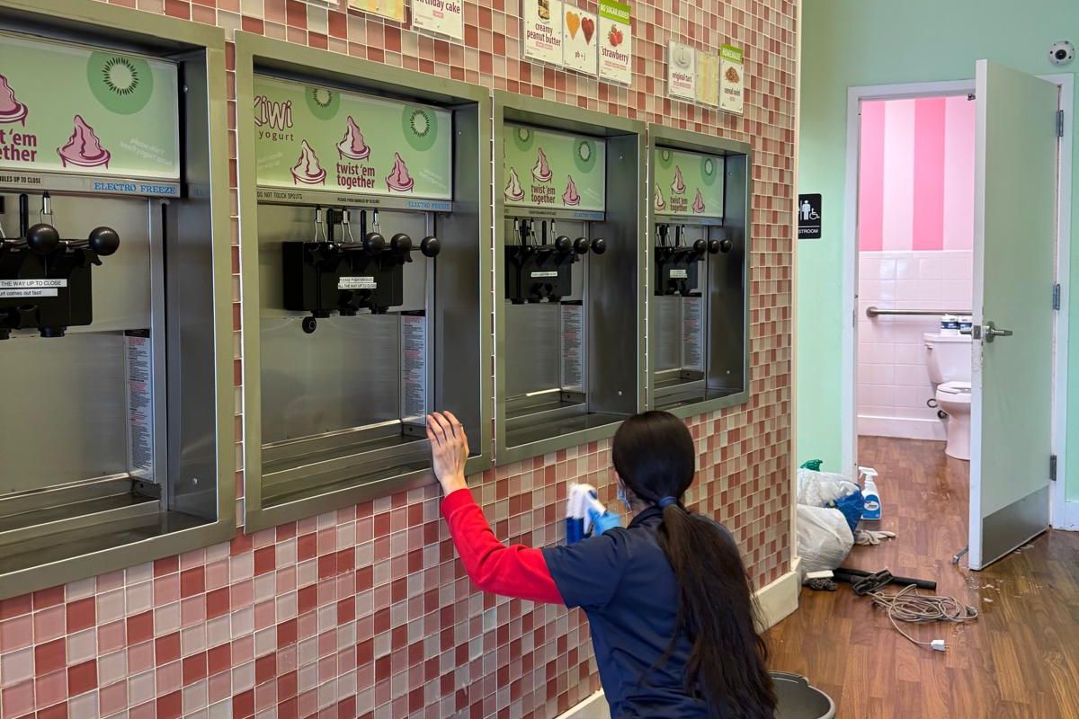 Maggie's Magic Touch team member cleaning the tile wall of a local business